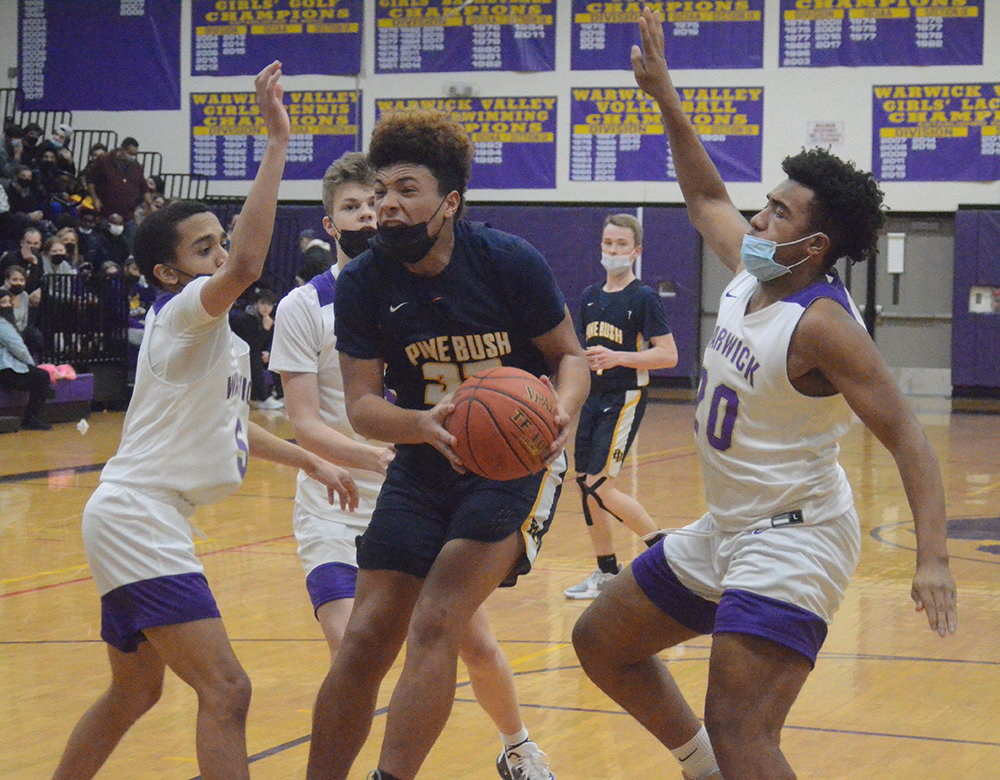 Pine Bush’s Dion Cauthen grabs a rebound as he is surrounded by Warwick’s Jonah Mederos (5), Josiah Jones (21) and Latrell Willis (20) during Friday’s OCIAA Division II boys’ basketball game at Warwick Valley High School.